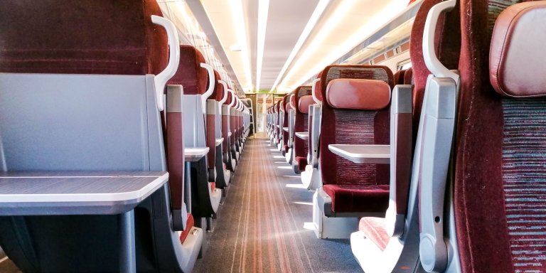 The interior of a train in Ireland with vibrant red seats.